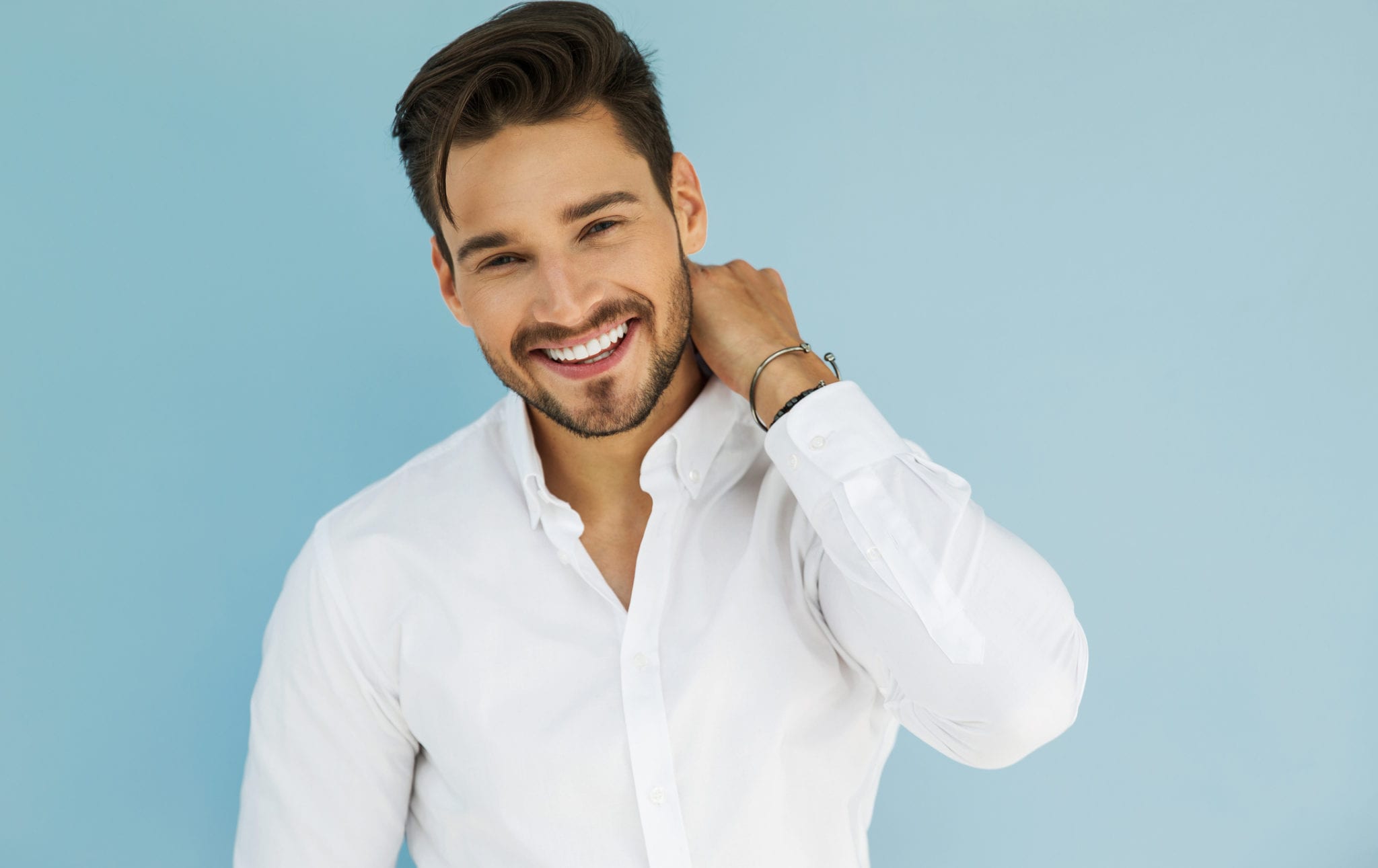 handsome young man smiling at the camera against a blue background