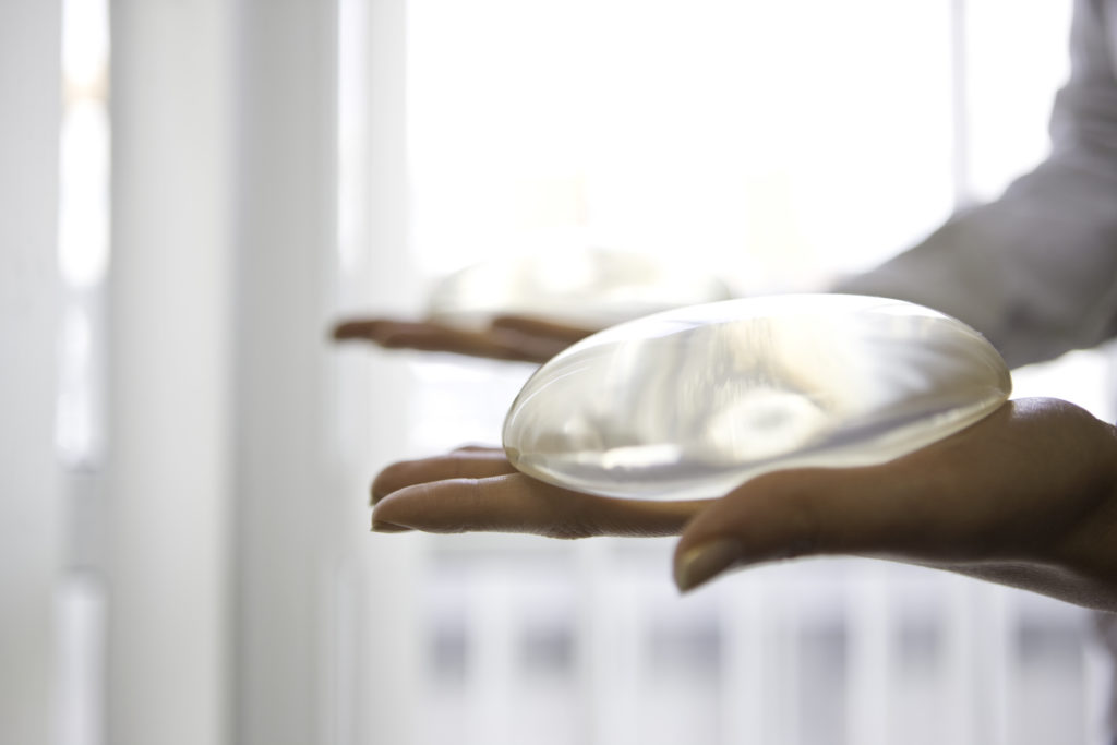 Close up of woman holding breast implants in hands