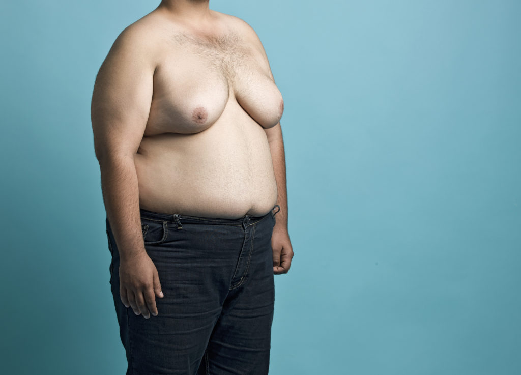 Obese young man shirtless on blue background, midsection
