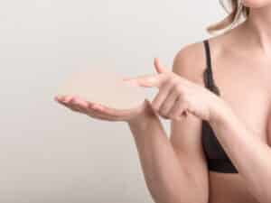 A close-up shot of a woman holding a breast implant after removal
