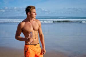 A shirtless man walking on the beach