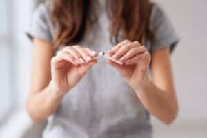 A woman breaking a cigarette in half to support tummy tuck recovery