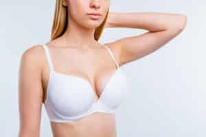 Cropped shot of a woman in a white bra after getting breast implants